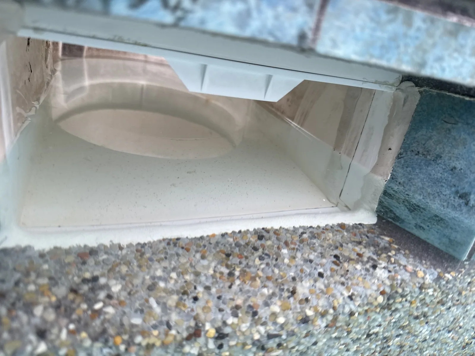 Brand new pool skimmer installed with a clean pebble deck finish after leak repair