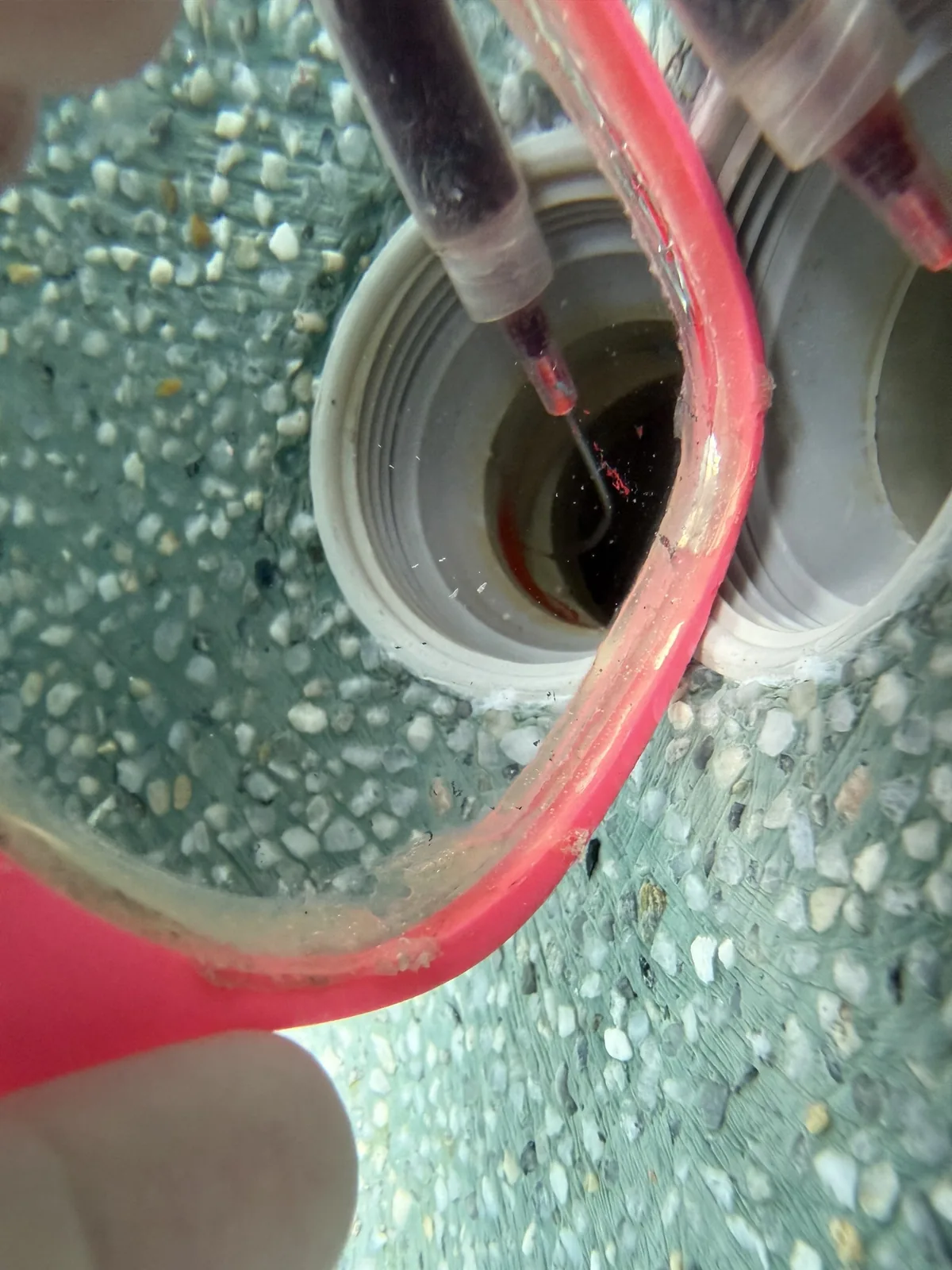Dye syringe confirming a leak at a pool return fitting during an Advanced Leak Detection inspection