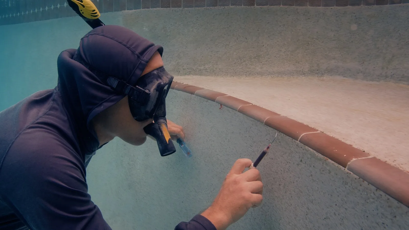 Diver recording inspection notes at the pool edge for a detailed leak detection report