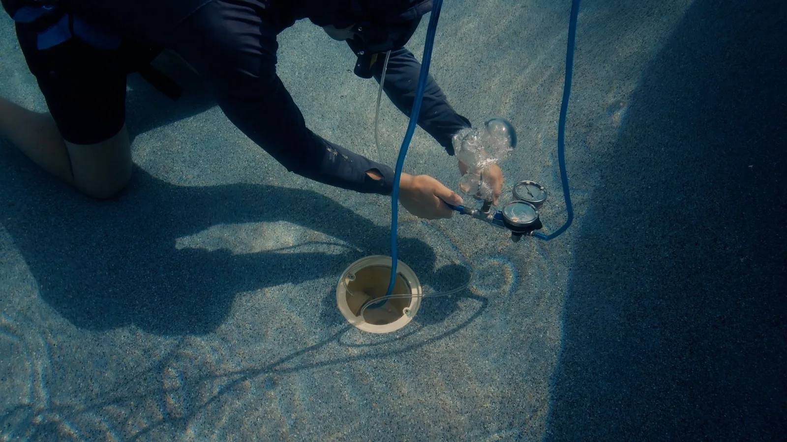 Technician performing an underwater dye test at a pool main drain in Tampa Bay
