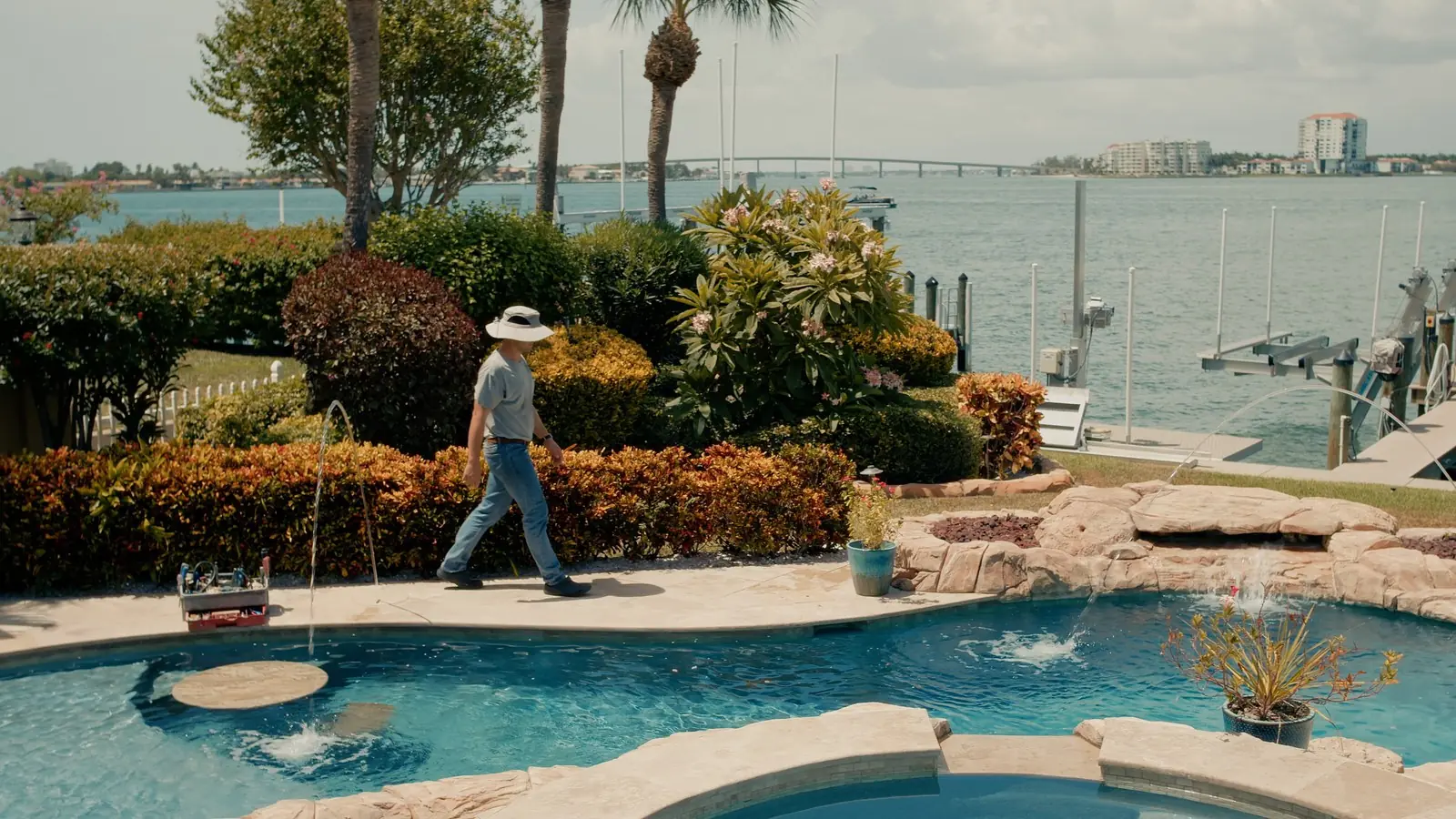 Advanced Leak Detection technician carrying equipment at a waterfront pool on Sarasota Bay